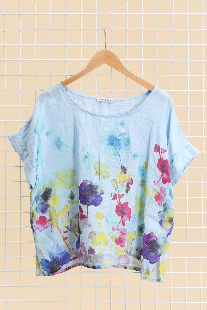 Light blue Italian linen blouse featuring delicate floral print, short sleeves, and relaxed fit.