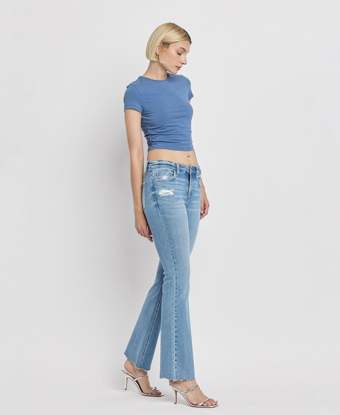 Side view of women's mid-rise bootcut jeans featuring flattering silhouette and raw hem