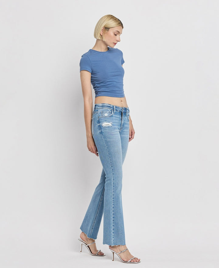 Side view of women's mid-rise bootcut jeans featuring flattering silhouette and raw hem