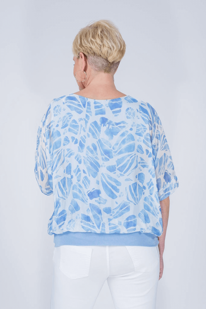 Back view of Italian-made celestial blue silk blouse featuring elegant tropical design and relaxed fit