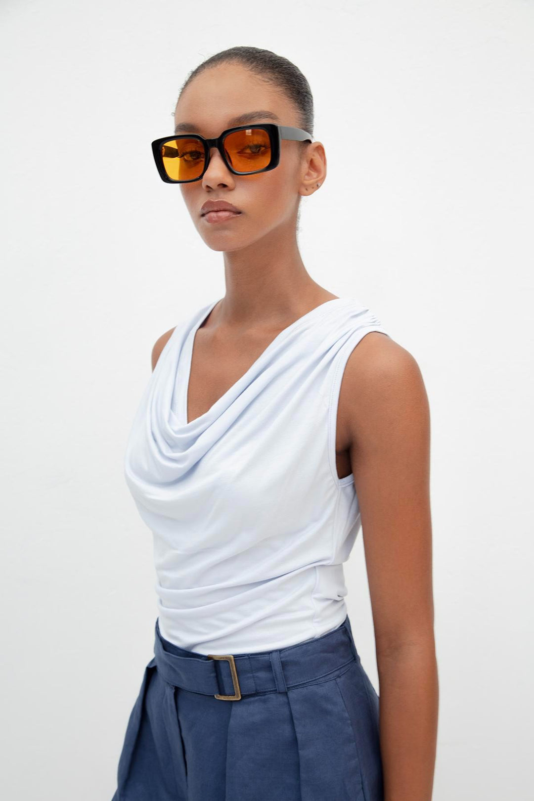 Side view of women's light blue sleeveless top with ruffle collar and flowing silhouette