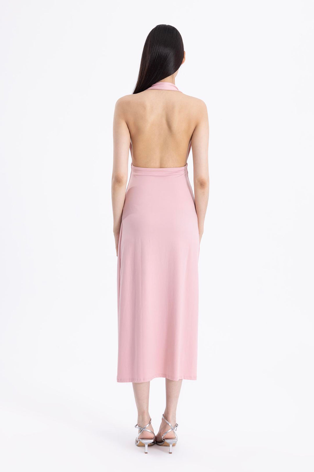Back view of pink draped midi dress featuring minimal back cut and soft fabric movement