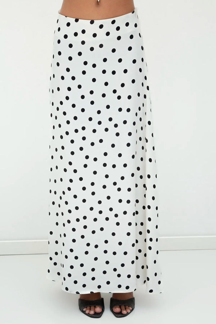 Close-up of 100% viscose satin fabric in ecru with black polka dots, showcasing smooth texture