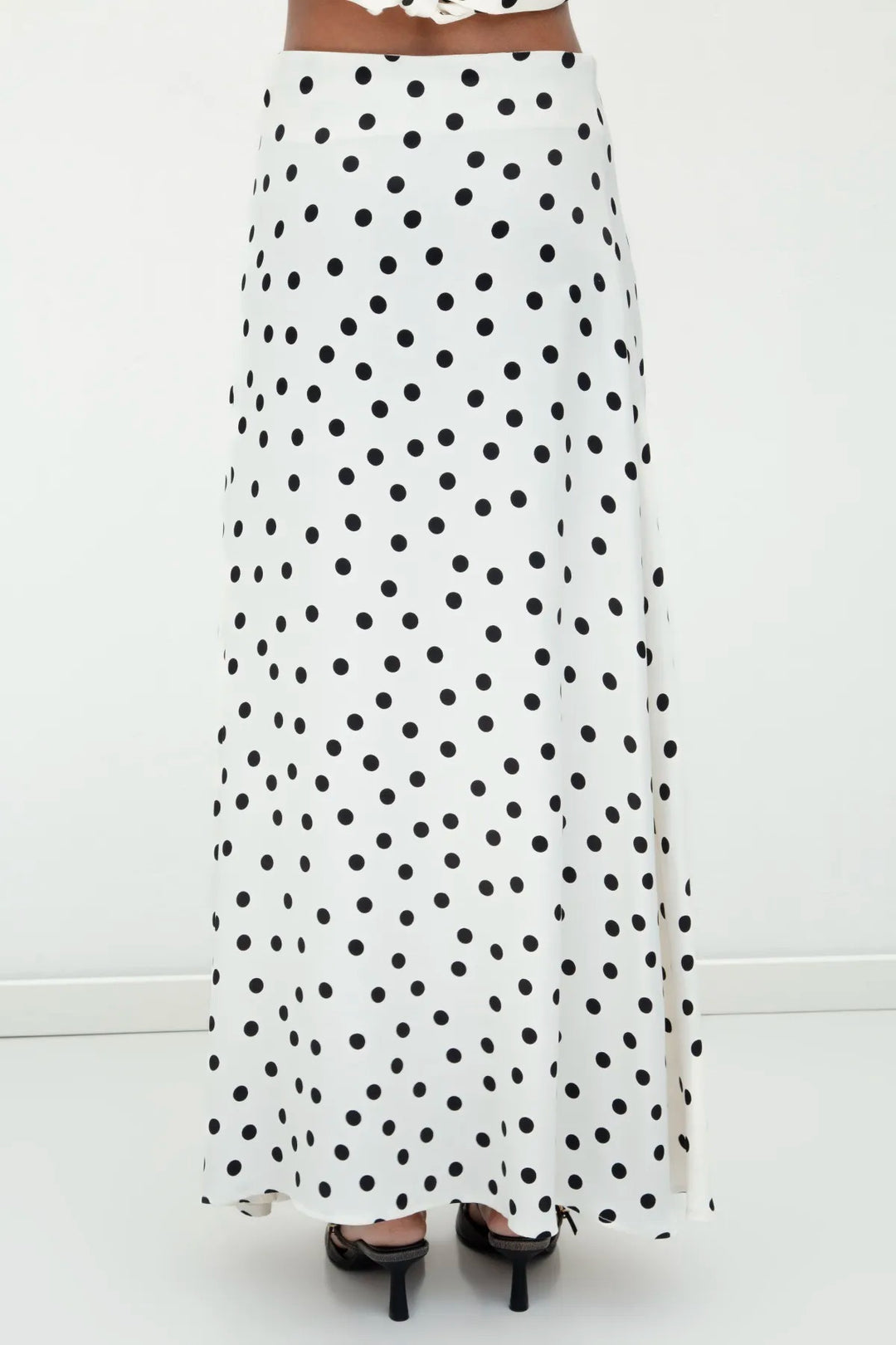 Back view of ecru satin long skirt featuring black polka dots and a graceful flow