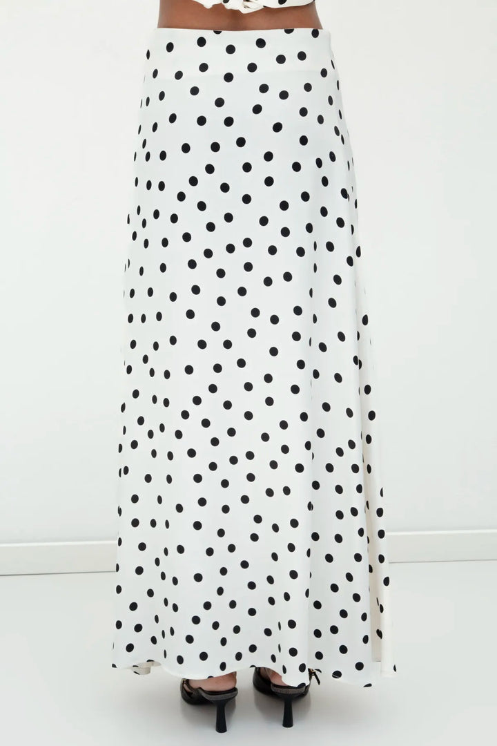 Back view of ecru satin long skirt featuring black polka dots and a graceful flow