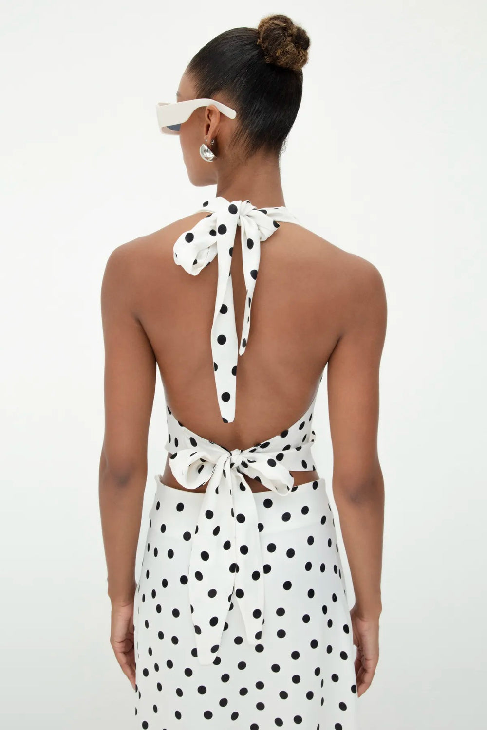 Back view of ecru satin top featuring an open-back design with tie closure and black polka dot pattern