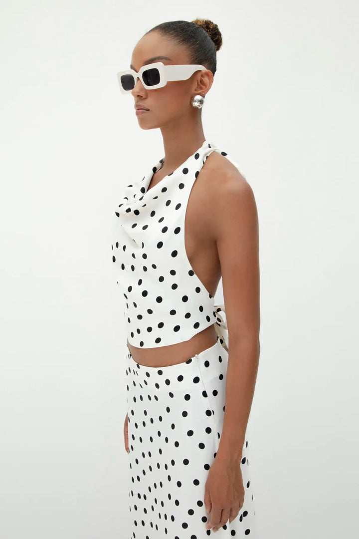 Side view of ecru satin top with black polka dots, highlighting its open-back design and flowy silhouette