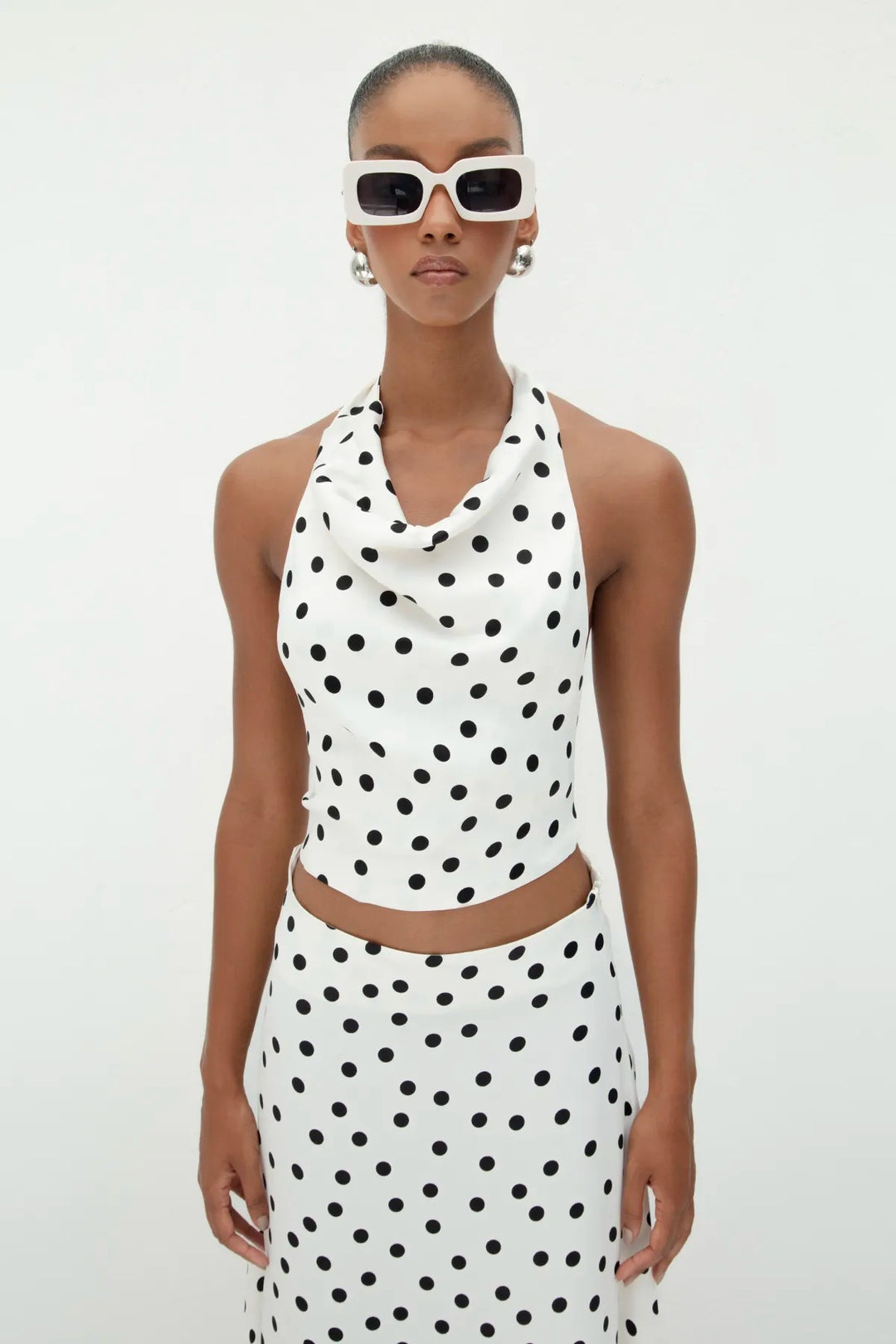 Close-up of 100% viscose satin fabric in ecru with black polka dots, showcasing smooth texture