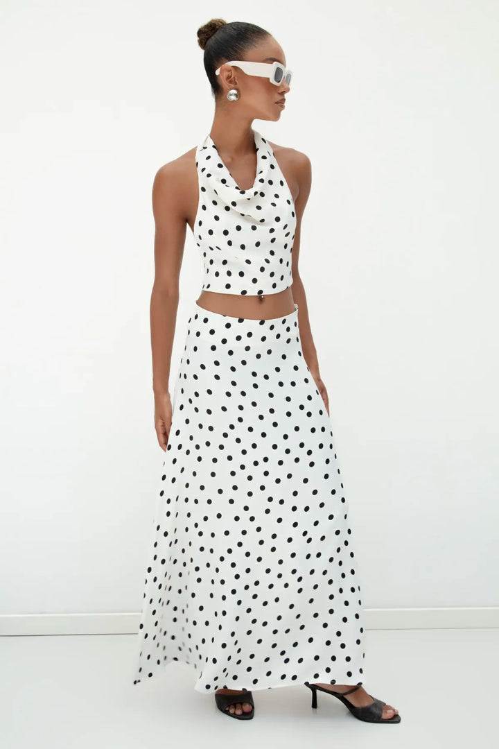 Chic outfit pairing ecru satin polka dot top with high-waisted jeans and heels – perfect for summer outings