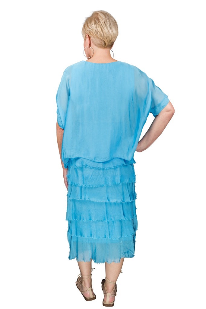 Back view of turquoise silk dress featuring tiered ruffle design and breezy movement