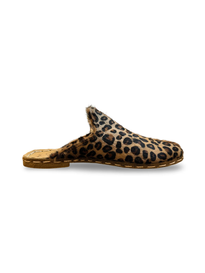 Side view of a women’s leopard-print slip-on slipper with a comfortable sole, isolated on a white background.