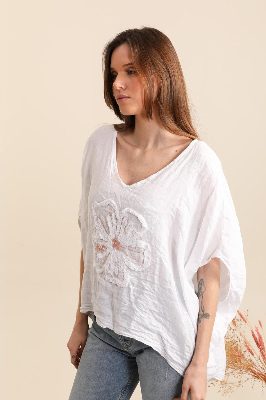 Side view of women's white linen blouse with floral embroidery and breezy silhouette