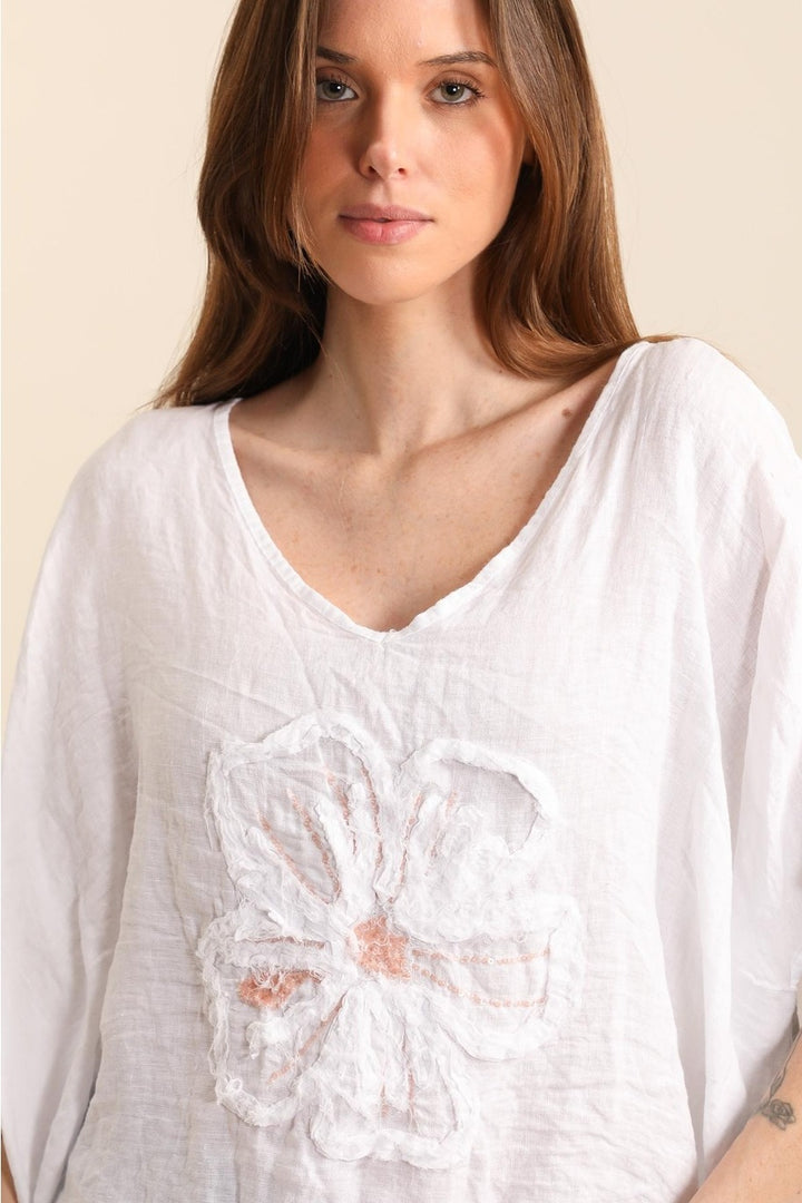 Close-up of 100% natural linen fabric in white, showcasing fine weave and floral embroidery detail