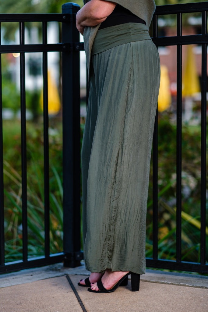 Side view of army green wide-leg silk pants with relaxed fit and foldover waistband