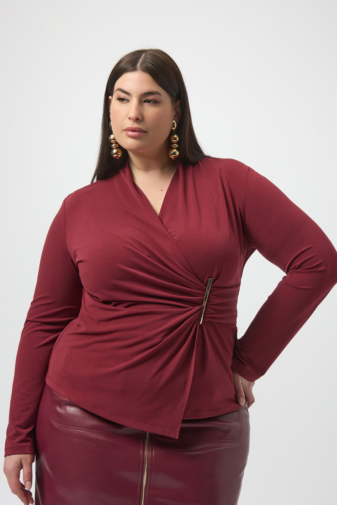 Woman wearing a burgundy top with a knot detail on a white background
