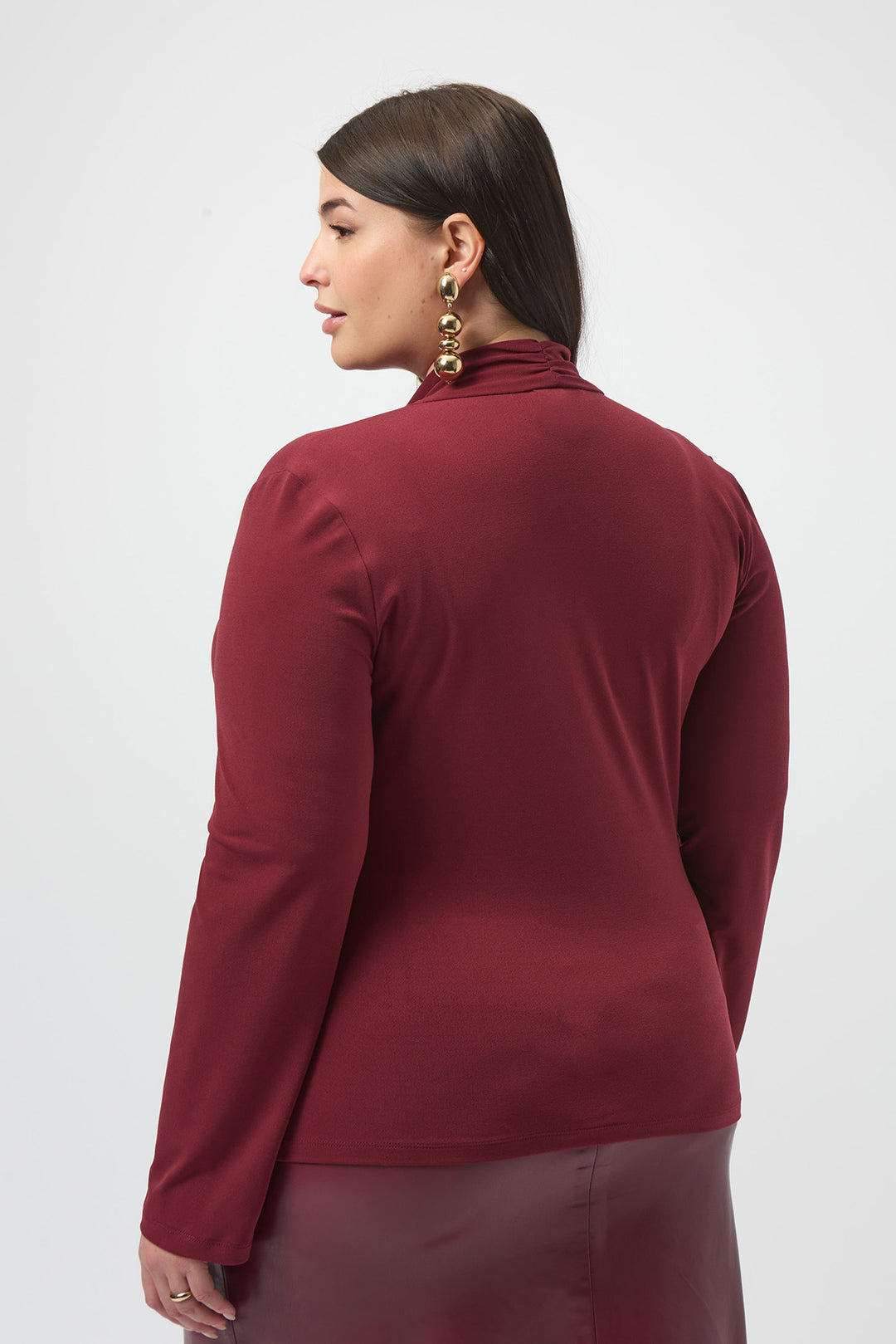 Woman wearing a burgundy long-sleeve top on a white background