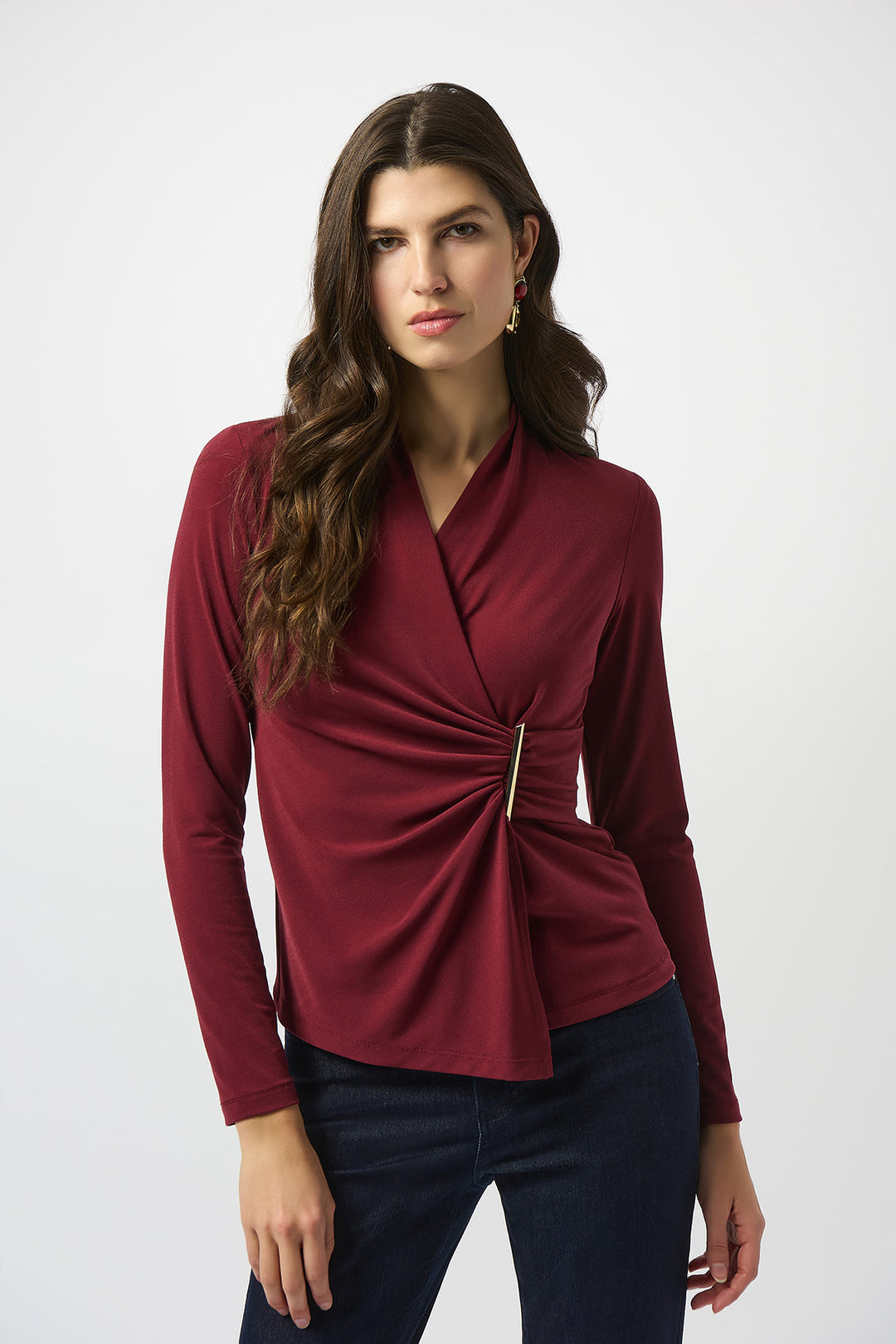 Woman wearing a burgundy long-sleeve top with a knot detail on a white background