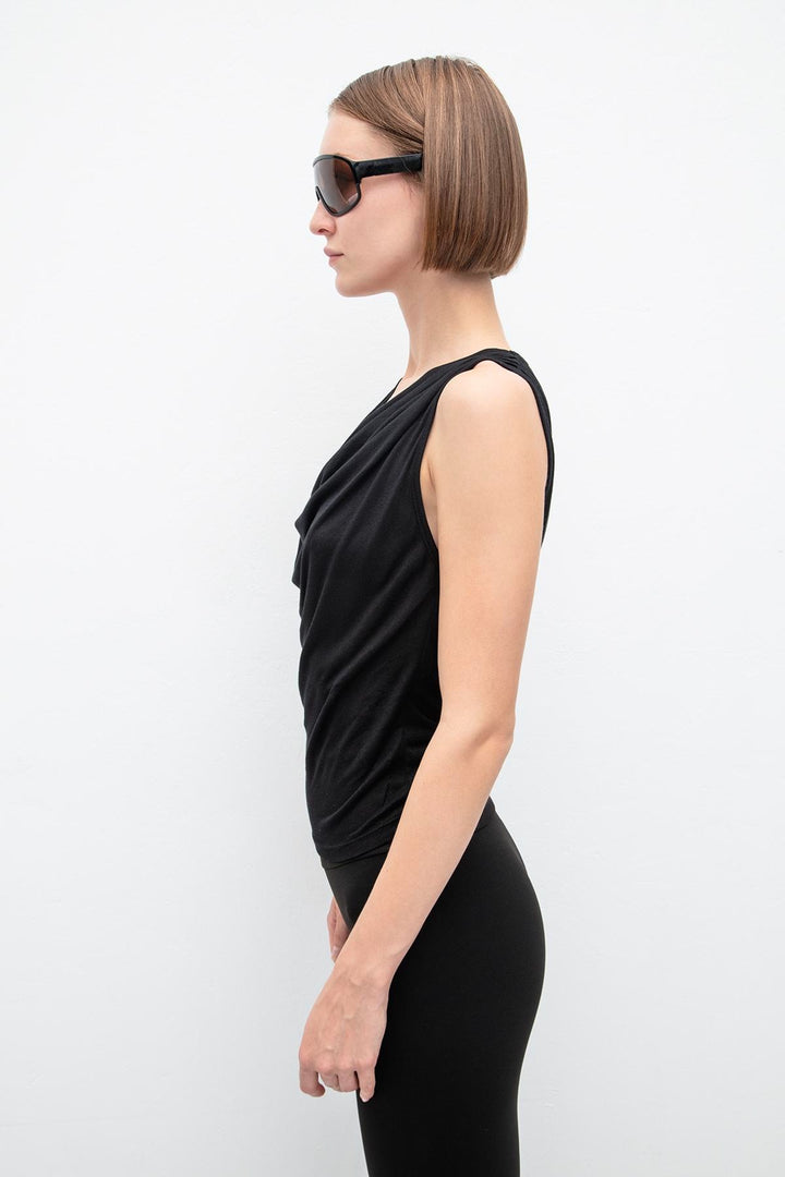 Side view of women's black sleeveless top with ruffle collar and flowing silhouette