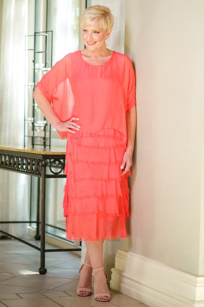 Side view of coral tiered silk dress featuring flowing layers and airy summer silhouette