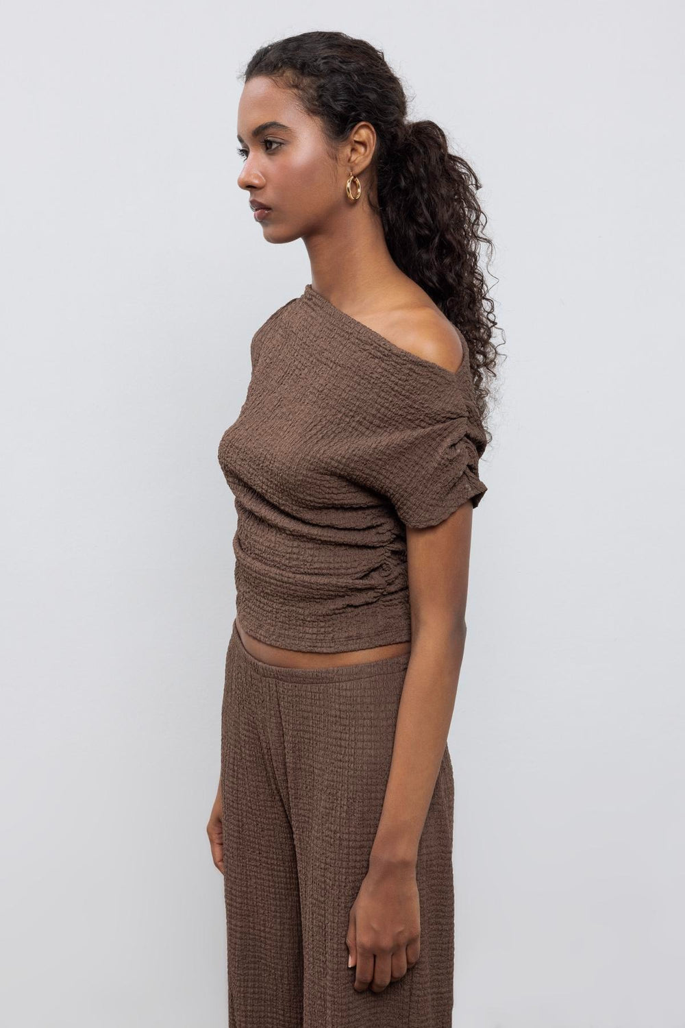 Chic outfit pairing brown textured top with high-waisted trousers – perfect for casual elegance