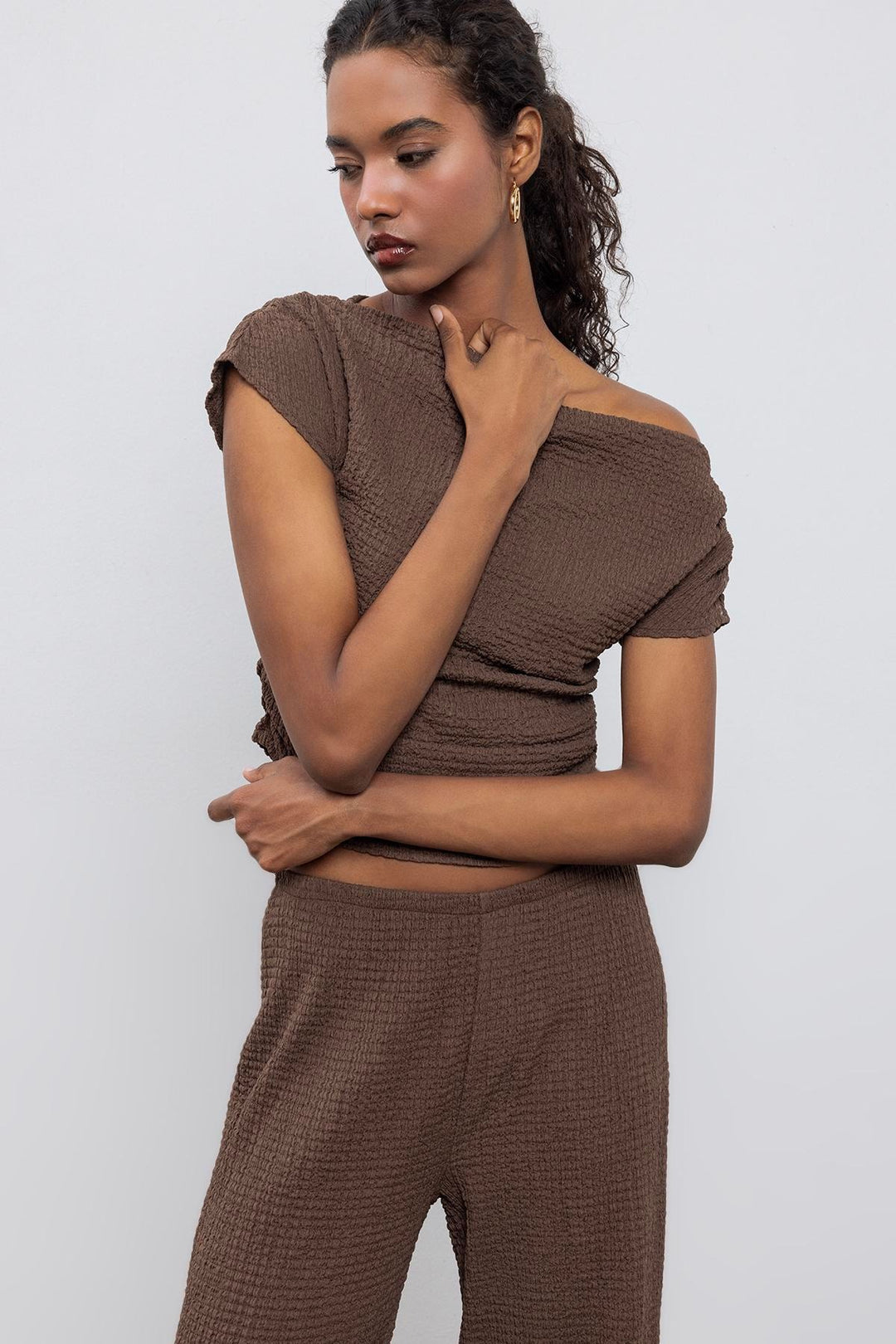 Chic outfit pairing brown textured top with high-waisted trousers – perfect for casual elegance