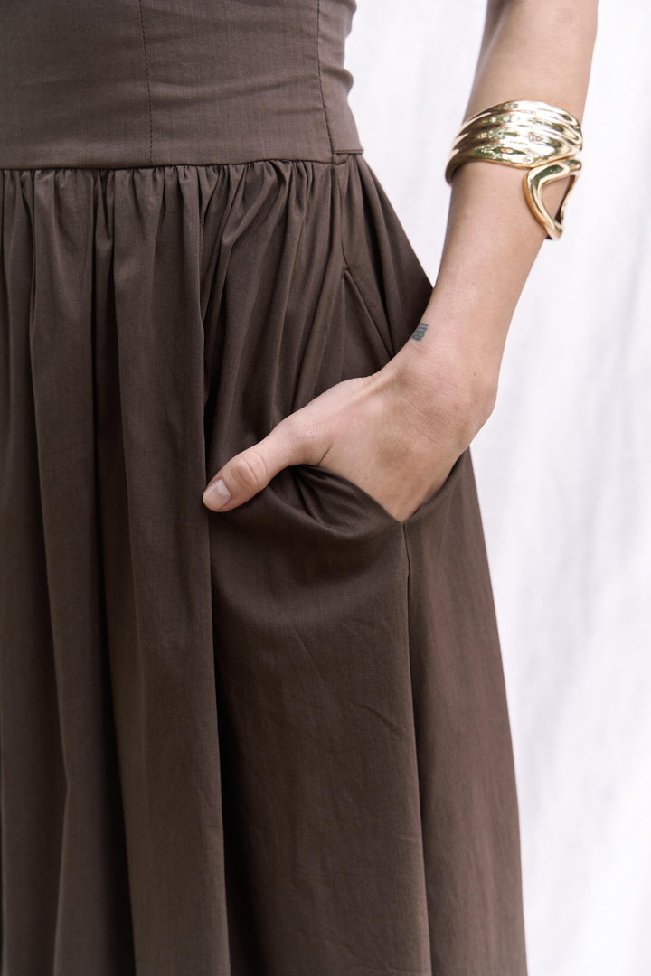 Brown dress with a hand in the pocket against a white background