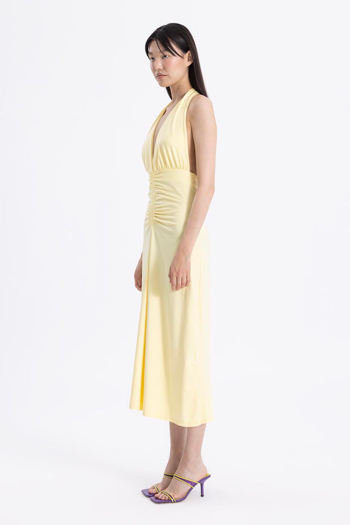 Side view of women's butter yellow draped midi dress with sleeveless design and elegant drape