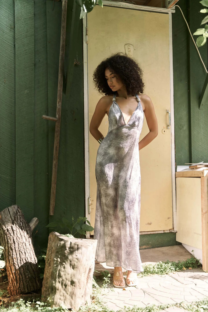 Woman in a silver dress standing in front of a green building.