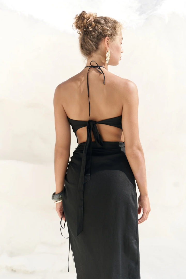 Woman wearing a black halter neck dress with a plain background