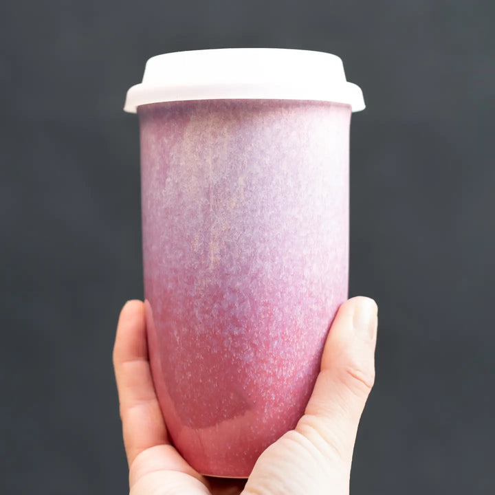 Hand holding a purple gradient tumbler against a dark background