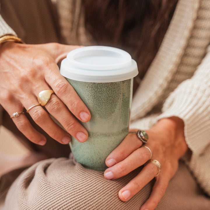 Person holding a textured green cup with a white lid