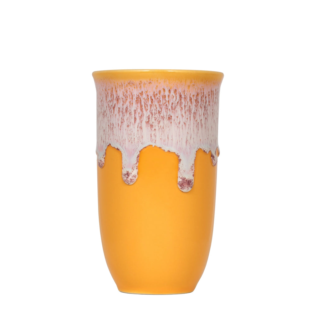 A yellow ceramic cup with a dripping pink and white glaze, shown against a plain white background.