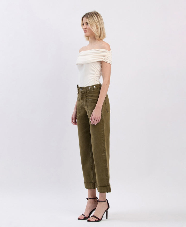 Woman wearing a white off-shoulder top and olive green pants on a white background