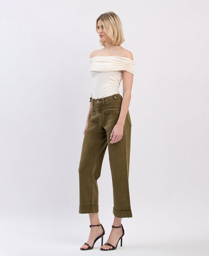Woman wearing a white off-shoulder top and olive green pants on a white background