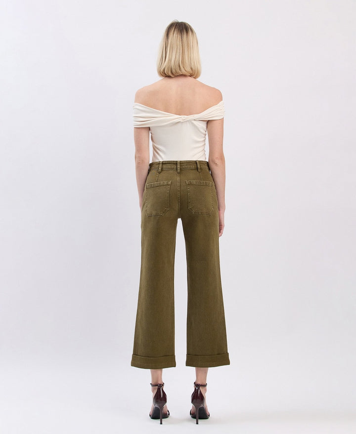 Woman wearing a white off-shoulder top and olive green wide-leg pants on a white background