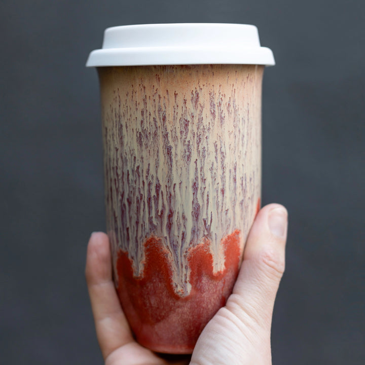 Hand holding a paper cup with a unique design against a dark background