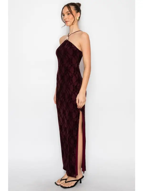 Woman wearing a burgundy evening gown with a slit on a white background