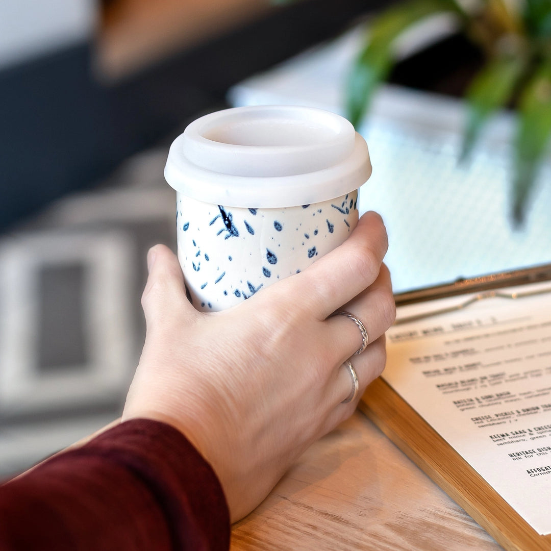 Hand holding a patterned coffee cup with a blurred background
