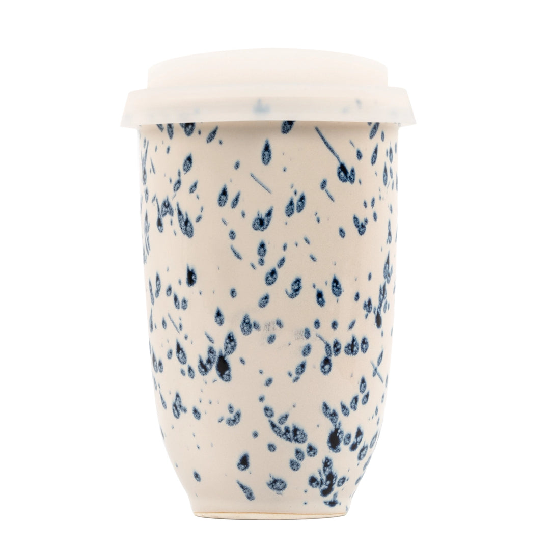 Ceramic mug with blue speckled pattern and white lid on a white background
