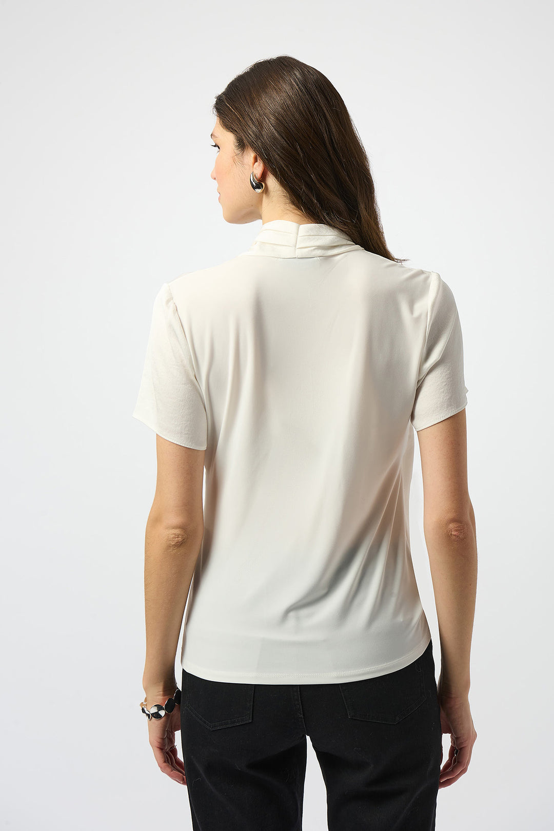 Woman wearing a white polo shirt and black pants on a white background