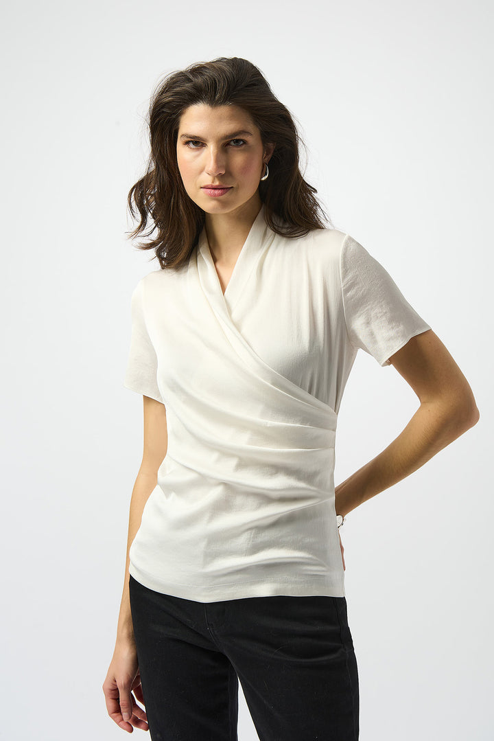 Woman wearing a white short-sleeve top with a draped neckline on a white background