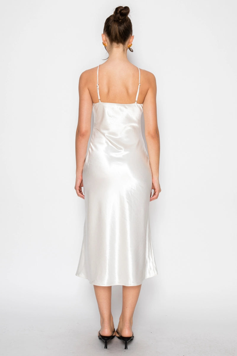 Woman wearing a white satin slip dress on a plain background
