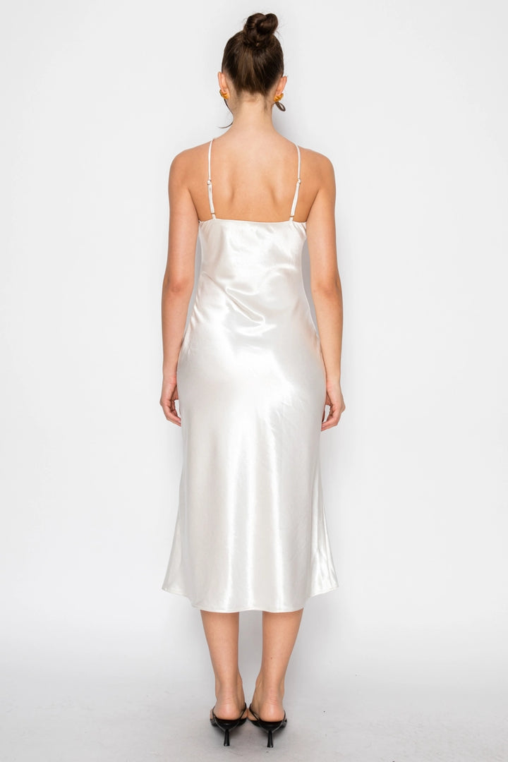 Woman wearing a white satin slip dress on a plain background