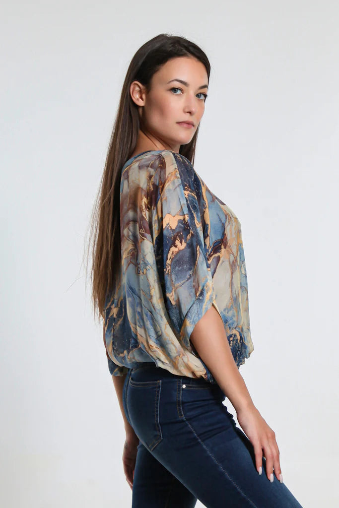 Side view of women's navy marble print silk top with sheer sleeves and flattering banded waist.