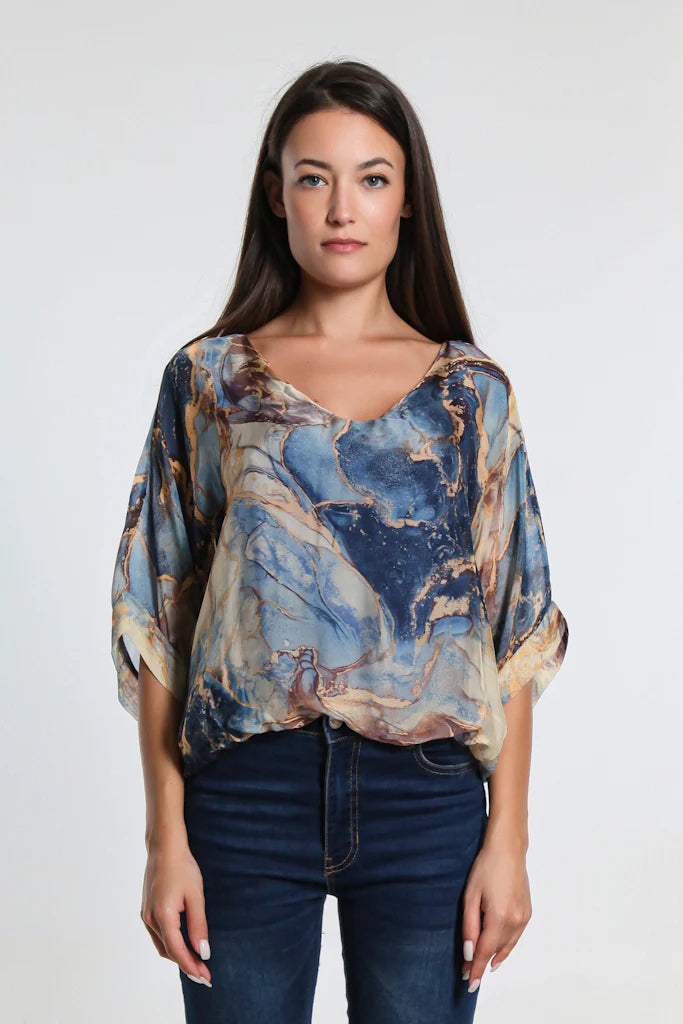 Stylish outfit pairing navy marble print silk top with jeans – versatile look for day or night.
