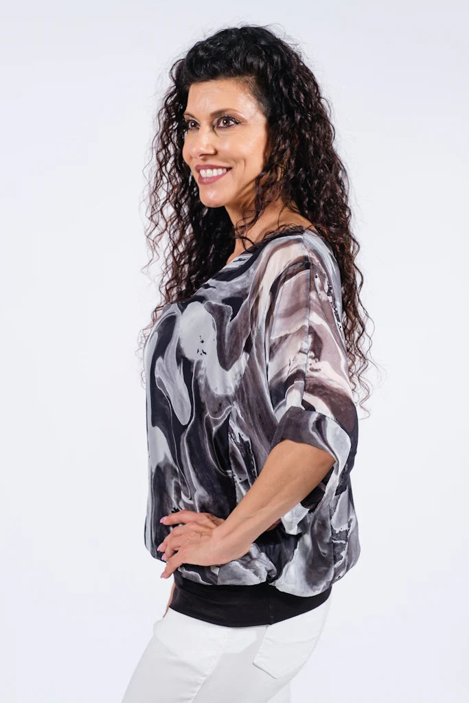 Side view of women's black swirl print silk top with sheer sleeves and flattering banded waist