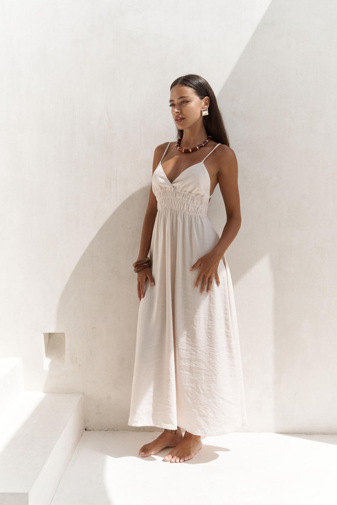Woman in a white dress standing against a white wall