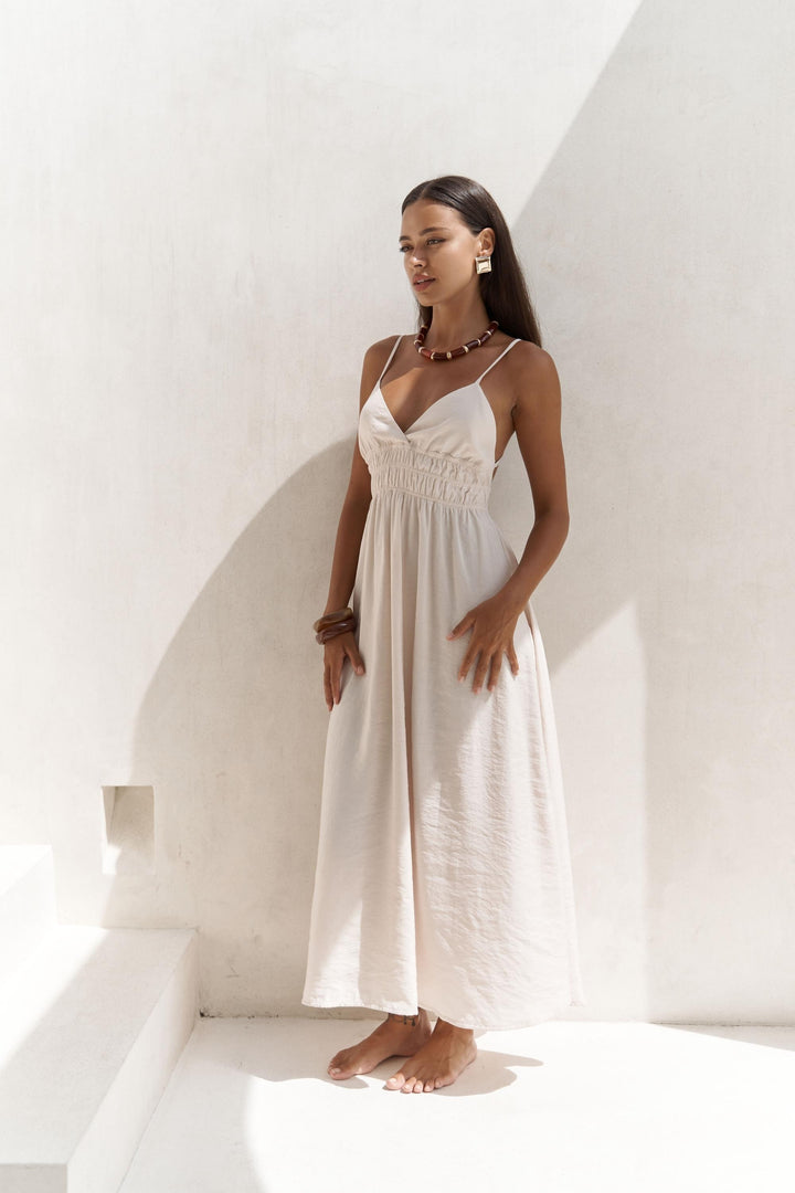 Woman in a white dress standing against a white wall