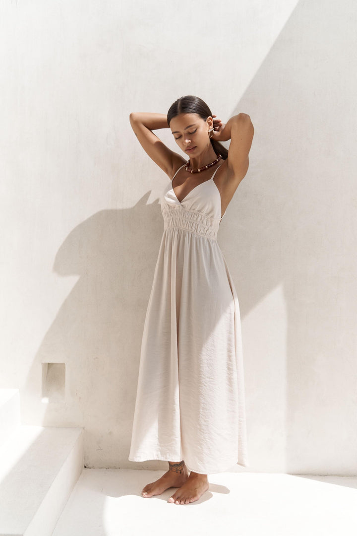 Woman in a white dress standing against a white wall