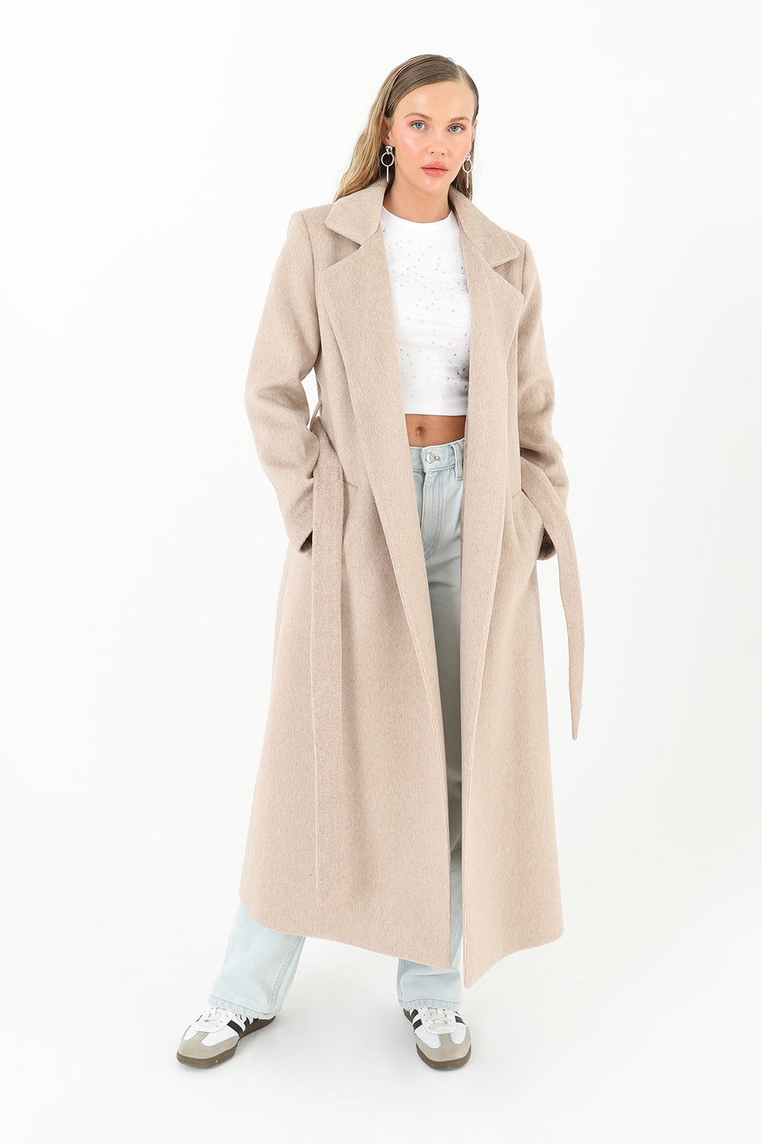 Woman wearing a long beige coat on a white background
